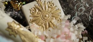 Närbild av utsmyckat julpynt i guld, silver, vitt och rosa, med en stor solformad dekoration i centrum