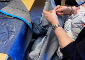 En kvinna syr i ett par gamla jeans