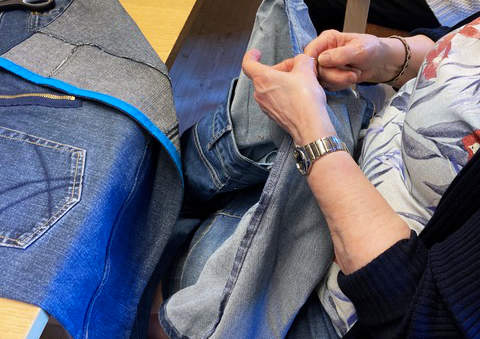 En kvinna syr i ett par gamla jeans