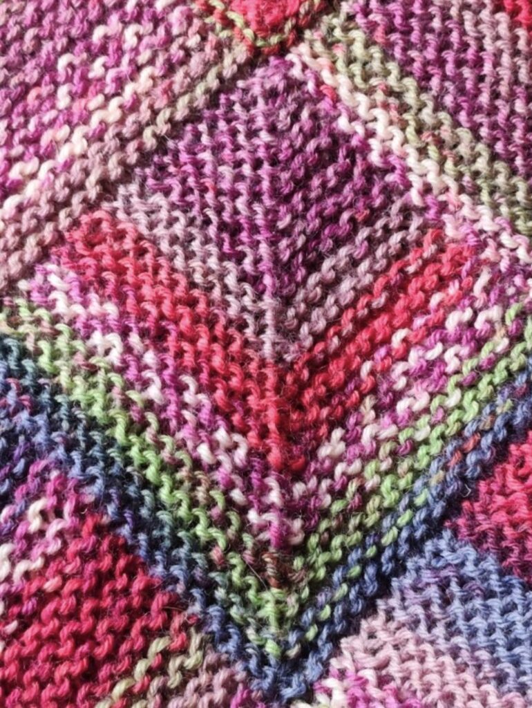 Färgglad dominostickad textil i rosa, lila, rött, grönt och blått