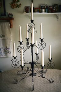 Ljusstake med flera vita stearinljus, handsmidd i svart tvinnad tråd med spiralformade detaljer