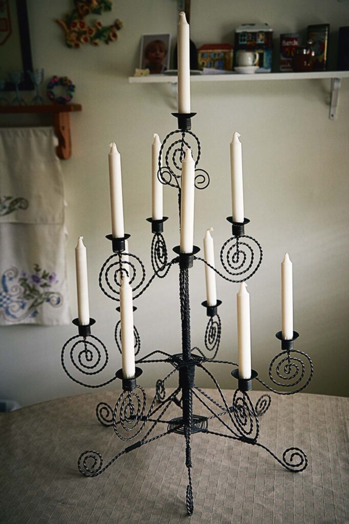 Ljusstake med flera vita stearinljus, handsmidd i svart tvinnad tråd med spiralformade detaljer