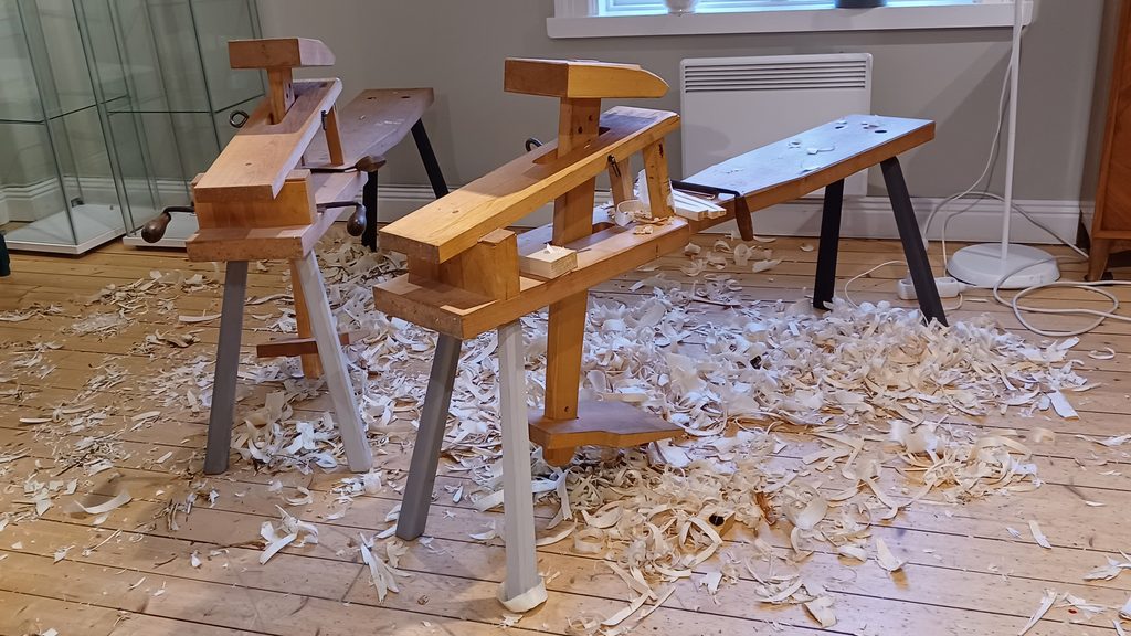 Täljhästar och andra träbearbetningsverktyg i en slöjdlokal, omgivna av träspån