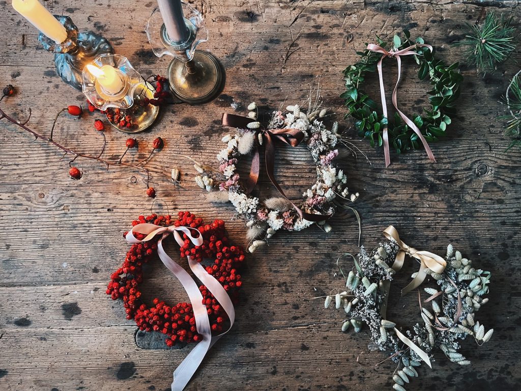 Olika handbundna kransar av torkade blommor, bär och gröna växter på ett träbord