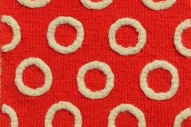 Röd stickad ruta med vita broderade ringar