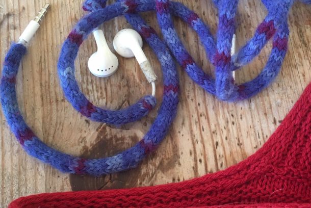 Här har sladden till ett par hörlurar fått en stickad snodd / i-cord som gör att den inte trasslar sig.