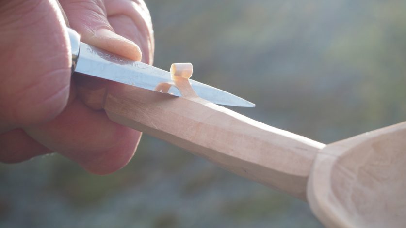 Närbild på hand som täljer med Morakniv.