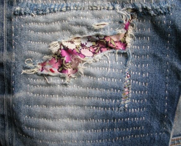 Blå jeans lappade med sashiko-teknik, här i form av rosa lapp med blommor på
