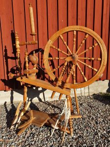 spinnrock och kardor framför en faluröd trävägg