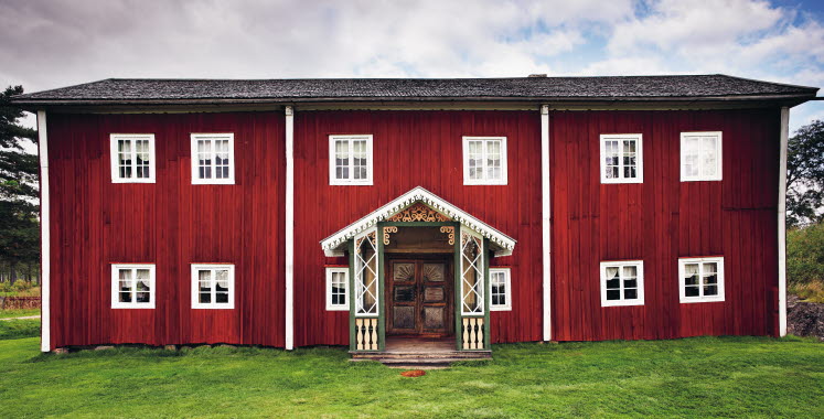 avlångt rött hus med snickarglädje på verandan - platsen är Fågelsjö