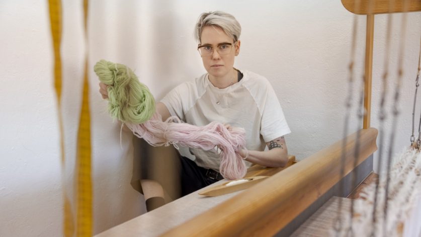 Textilkonstnär Morris Åkermalm med garner vid vävstol.