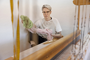 Textilkonstnär Morris Åkermalm med garner vid vävstol.