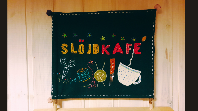 Yllebroderi med bilder av olika redskap och texten slöjdkafe